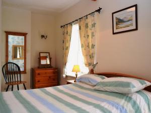 a bedroom with a bed and a chair and a window at Gable Cottage in Keswick