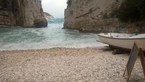 a boat on a rocky beach next to the water at Holiday home Stiniva in Vis