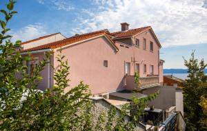 a large pink house on a hill with trees at Awesome Apartment In Omisalj With Wifi in Omišalj +21 photos