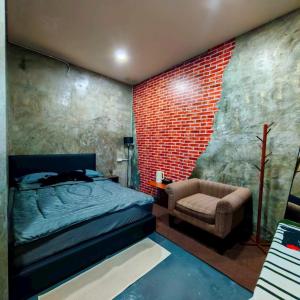 a bedroom with a brick wall and a bed and a chair at KM Pool Spa Resort in Ban Thale Thai Khao (1) +7 photos