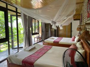 2 Betten in einem Zimmer mit Fenstern in der Unterkunft Nha Tan - Mai Chau Homestay & Tours in Mai Châu