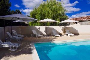 a swimming pool with chairs and umbrellas next to at Chez Fins Bois in Néré