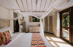a bedroom with a white bed with a white ceiling at Burudika Bungalows - Villas, Sauna & Bath House in Selong Belanak