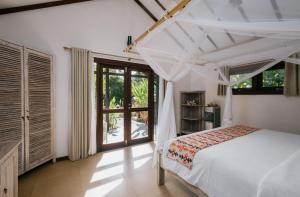 a bedroom with a bed and a large window at Burudika Bungalows - Villas, Sauna & Bath House in Selong Belanak
