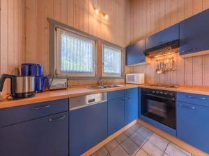 a kitchen with blue cabinets and a stove top oven at Ferienhaus mit Sauna im Ferienpark Mirow in Granzow +12 photos