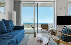 a living room with a blue couch and a view of the ocean at Awesome Apartment In Allinge With Wifi in Allinge