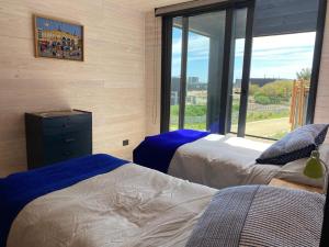a bedroom with two beds and a large window at Calm and beautiful beach in Pichilemu