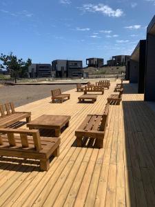 a row of wooden benches sitting on a wooden deck at Calm and beautiful beach in Pichilemu