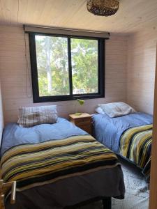 two beds in a room with a window at Calm and beautiful beach in Pichilemu +3 photos