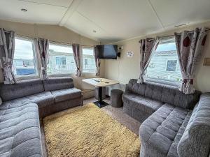 a living room with two couches and a table at Lovely 6 Berth Caravan At Seawick Holiday Park In Essex Ref 27008S in Clacton-on-Sea