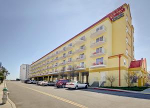 a large yellow building with cars parked in a parking lot at Bonita Beach Hotel in Ocean City