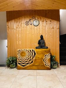 a statue sitting on top of a wooden wall with a clock at Casa Kasauli in Kasauli