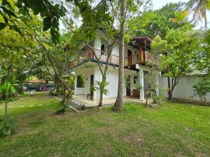 a house with a balcony in the middle of a yard at Augmented Kabalana in Ahangama