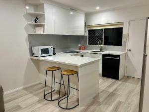 a kitchen with a counter with two stools and a microwave at The Lazy Break at Trinity in Trinity Beach
