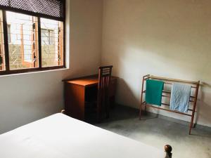 een slaapkamer met een bed, een bureau en een raam bij Selene House in Hikkaduwa