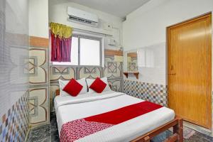 a bedroom with a bed with red pillows and a window at Hotel O RKR Residency in Chennai