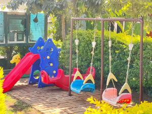 a childrens playground with a slide and swings at Abu Residency in Kodaikānāl