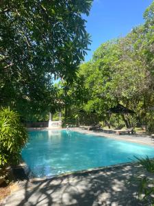 a swimming pool with blue water and trees at Ginganga Lodge in Galle