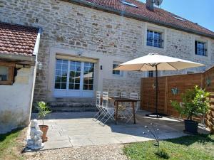 a patio with a table and an umbrella at La cabane de Lancelot Loubliette in Laperrière-sur-Saône