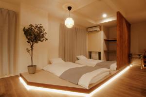 a bedroom with two beds and a potted plant at LikeINN札幌スイーズS4 in Sapporo