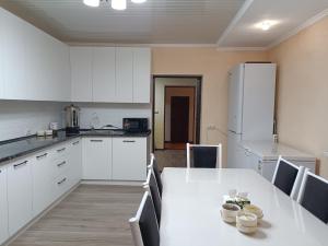 a kitchen with a table with chairs and a refrigerator at Guest House South Wind in Pokrovka