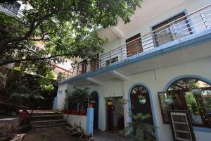 a white house with a balcony on top of it at Crescent Moon Homestay in Rishīkesh