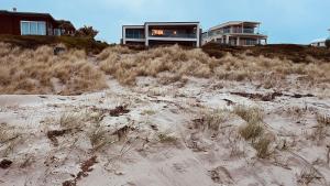 a house sitting on top of a sandy beach at Beachside Bliss in Tauranga