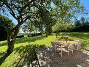 a table and chairs in a field with a tree at Le Hameau des Prés-Verts, un séjour détente et bien être pour les amoureux de la nature au cœur du Pays d'Auge, en Normandie in Les Champeaux +50 photos
