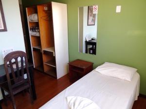 a bedroom with a bed and a mirror and a chair at Hotel Oriente in Itajubá