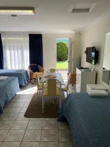 una camera da letto con due letti, un tavolo e delle sedie di Emu Point Motel a Albany