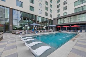 a swimming pool in a building with chairs and umbrellas at Cambria Hotel Austin Downtown in Austin