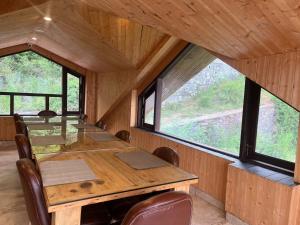 a dining room with a table and some windows at Casa Kasauli in Kasauli