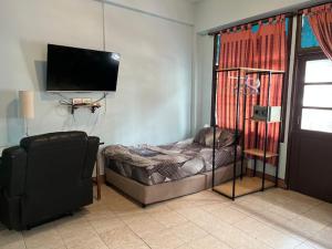 un salon avec un petit lit et une télévision dans l'établissement Baan Picha 2, à Pattaya
