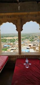 a room with two windows and a table with a red blanket at The Travellers Cup Fort Stay in Jaisalmer