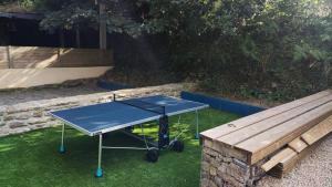 Una mesa de ping pong azul junto a un banco de madera en le petit moulin de Kerloroc, en Ploudalmézeau