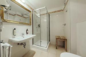 a white bathroom with a shower and a sink at Seehotel Schlierseer Hof in Schliersee +88 photos