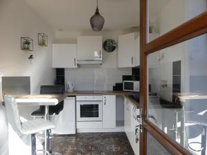 a kitchen with white cabinets and a table and chairs at Le Nî’ De Jess in Migennes