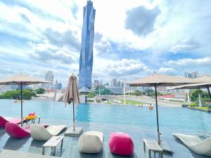 a pool with chairs and umbrellas in front of a city at Blue Haven Apartment at Opus Residence Kuala Lumpur in Kuala Lumpur