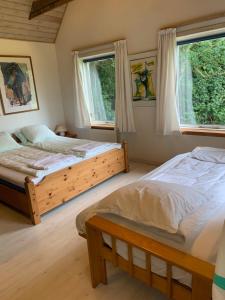 two beds in a bedroom with two windows at Casita amarilla in Helsinge +28 photos