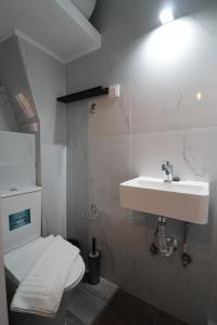 ein Badezimmer mit einem weißen Waschbecken und einer Toilette in der Unterkunft Venetian Vicolo by CorfuEscapes in Korfu-Stadt