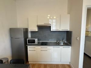 a kitchen with white cabinets and a sink and a refrigerator at Montsejour - Superbe T2 rénové in Tarbes