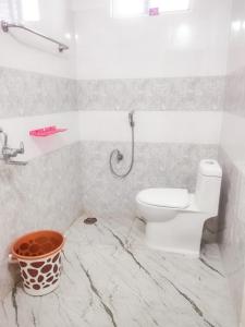 a bathroom with a toilet and a bucket in it at RKN Home Stays in Warangal