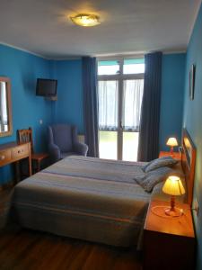 a bedroom with a bed and a chair and a window at Hotel Águila Real in Cangas de Onís