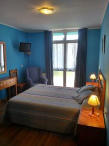 ein Schlafzimmer mit einem Bett, einem Stuhl und einem Fenster in der Unterkunft Hotel Águila Real in Cangas de Onís