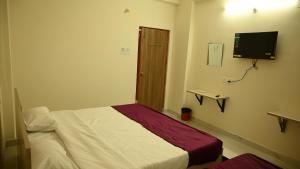 a bedroom with a bed and a tv on the wall at RKN Home Stays in Warangal