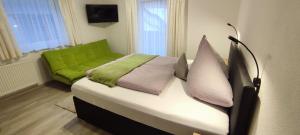 Una cama con un sofá verde en una habitación en Haus Alpenrose, en Sankt Leonhard im Pitztal