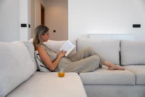 une femme assise sur un canapé en train de lire un livre dans l'établissement Aetheria & Aura Suites by Temma Villas, à Chersónissos 56 autres photos