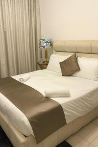 a large bed with white and brown sheets and pillows at Best Emaar Beachfront view one bedroom in Dubai