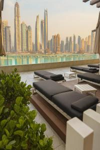 a row of chaise lounges on a rooftop with a city skyline at Best Emaar Beachfront view one bedroom in Dubai