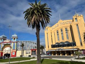 a palm tree in front of a large building at St Kilda Escape on Acland street in Melbourne +3 photos